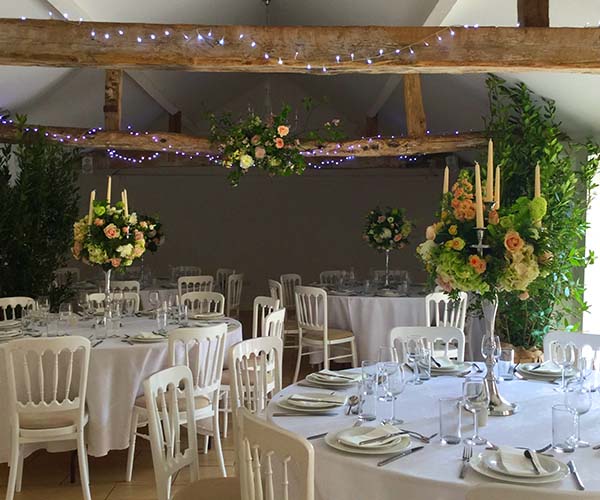 Tables prepared in a wedding venue that has wooden beams across the ceiling.